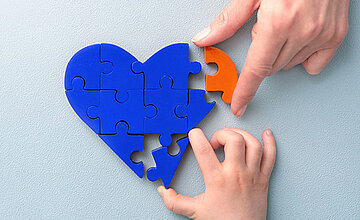 Engagement: Bild zeigt blaues Herz, in das ein oranger Puzzlestein eingefügt wird.